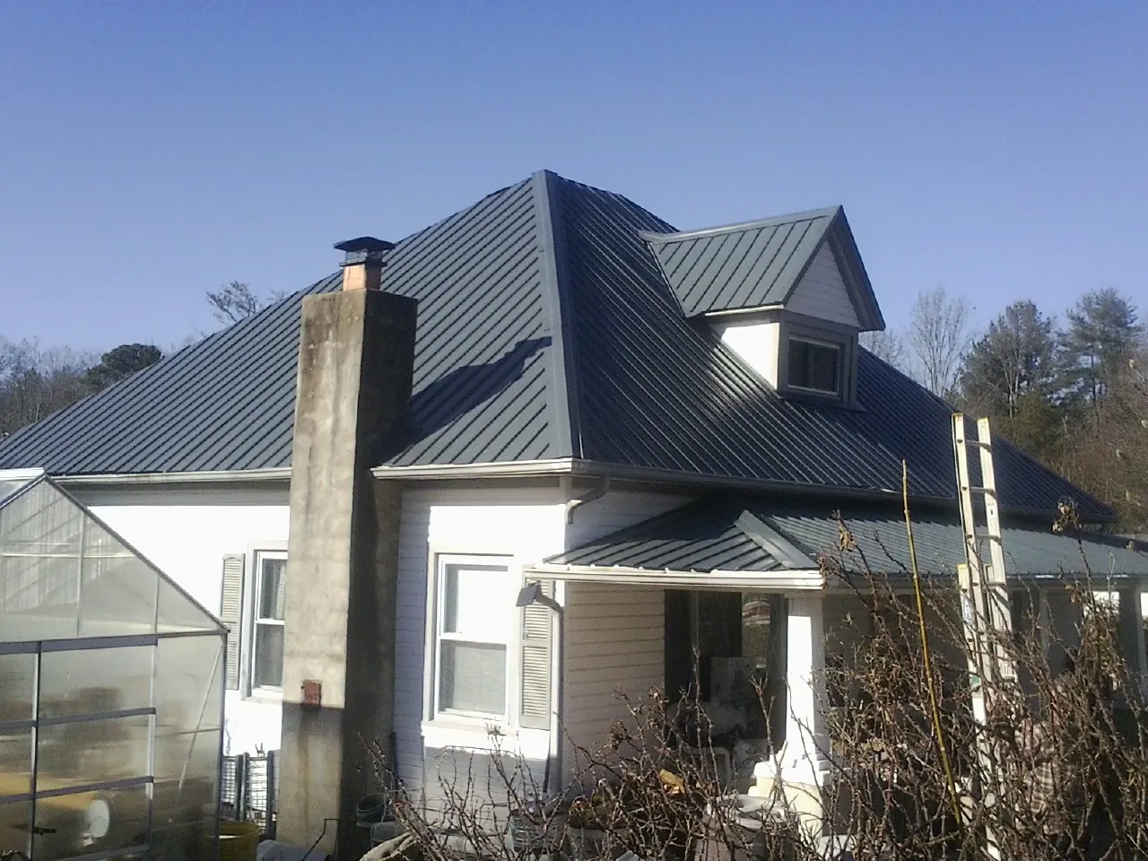 Dark blue standing seam metal roof on a white farmhouse with dormer — Slate & Tile Roof Repair by Roofing Brothers in Evans City