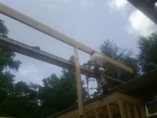 Carpenter setting a ridge beam over a new addition frame — Ice Dam Removal by Roofing Brothers in Evans City