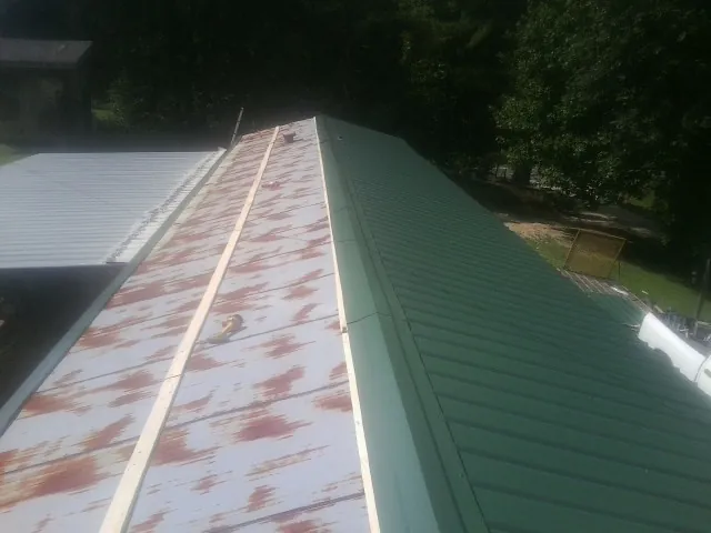 Old rusted panels beside newly installed green metal roofing — Wind Damage Roof Repair by Roofing Brothers in Evans City