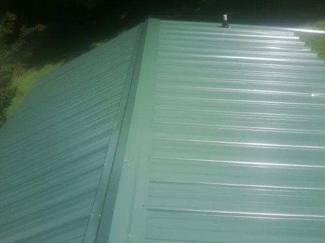 New green metal panels meeting at the ridge of a roof in Evans City