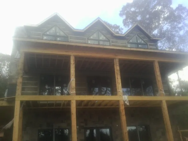 Dormers and porch framing on a large log home under construction — Roof Coating work by our crew in Evans City