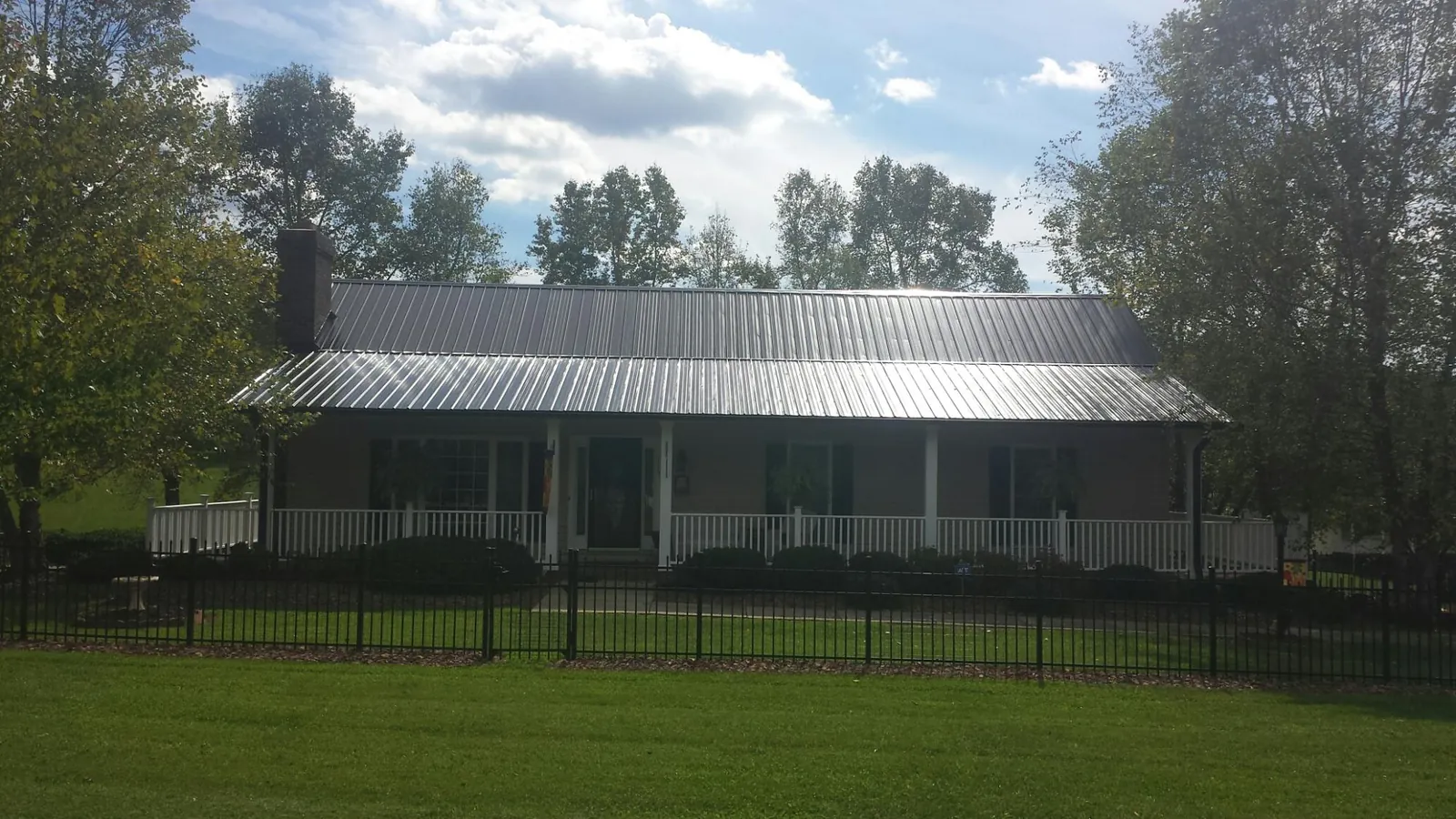 Gray metal roof on a brick ranch with a full width front porch — Gutter Guard Installation work by our crew in Evans City