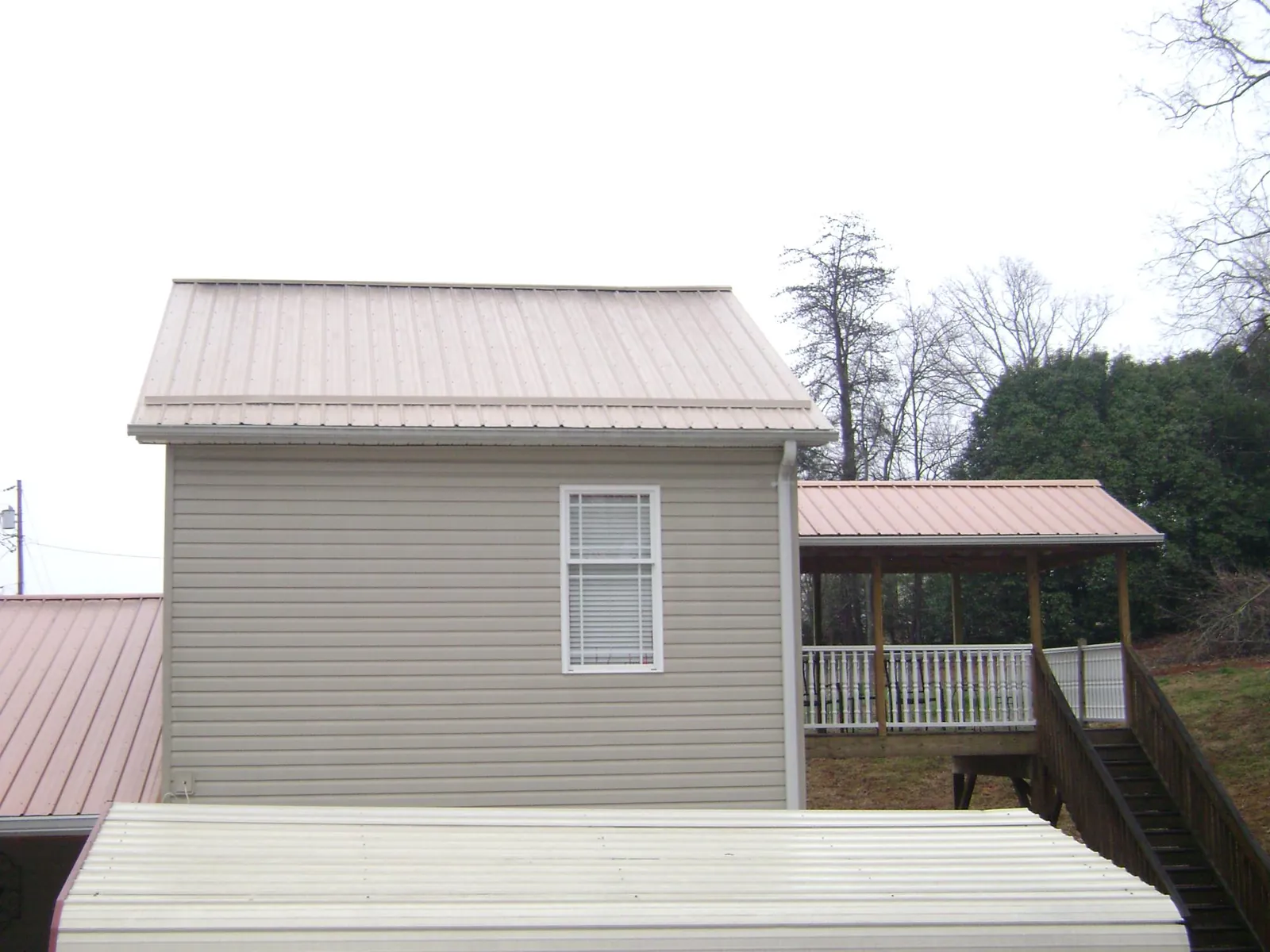 Tan metal roofs on a two story addition and attached porch, from a Roof Replacement job in Evans City