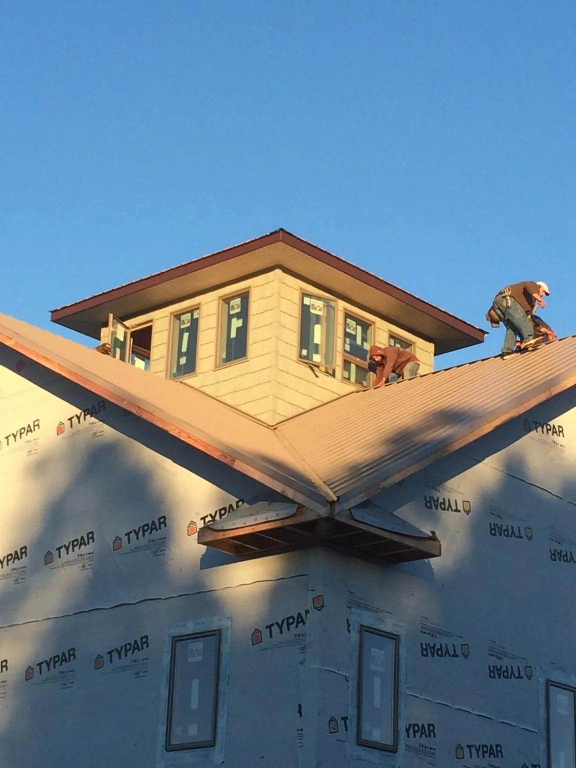 Roofers working around a rooftop cupola on a new metal roof at sunset — Roof Waterproofing in Evans City by Roofing Brothers